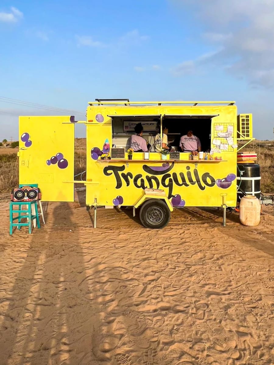 הפודטראק הצהוב של Tranquilo בחול, עם הצוות בחלון